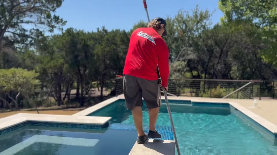 A Sullivan’s technician brushing along the tile line of a pool with an attached spa