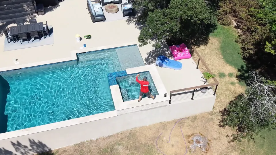 Aerial view of a backyard pool and attached spa, with a Sullivan’s technician working in the spa